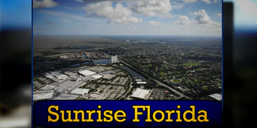 Aerial view of Sunrise, Florida, showing residential areas, commercial buildings, and surrounding landscape under a partly cloudy sky. Notably visible are tow trucks providing valuable towing services. The image has text at the bottom reading 