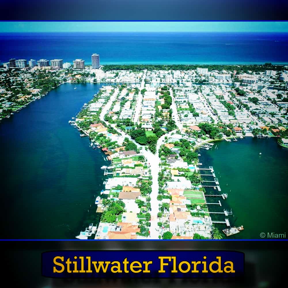 Aerial view of Stillwater, Florida, showing a residential area surrounded by water on three sides, with the ocean in the background. A tow truck is visible near the shoreline. Text at the bottom reads 