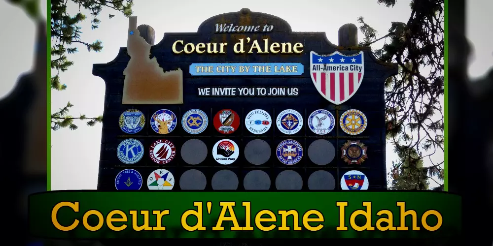 A welcome sign for Coeur d'Alene, Idaho, features the state outline and various logos, with a friendly tow truck graphic subtly integrated. The tagline reads 