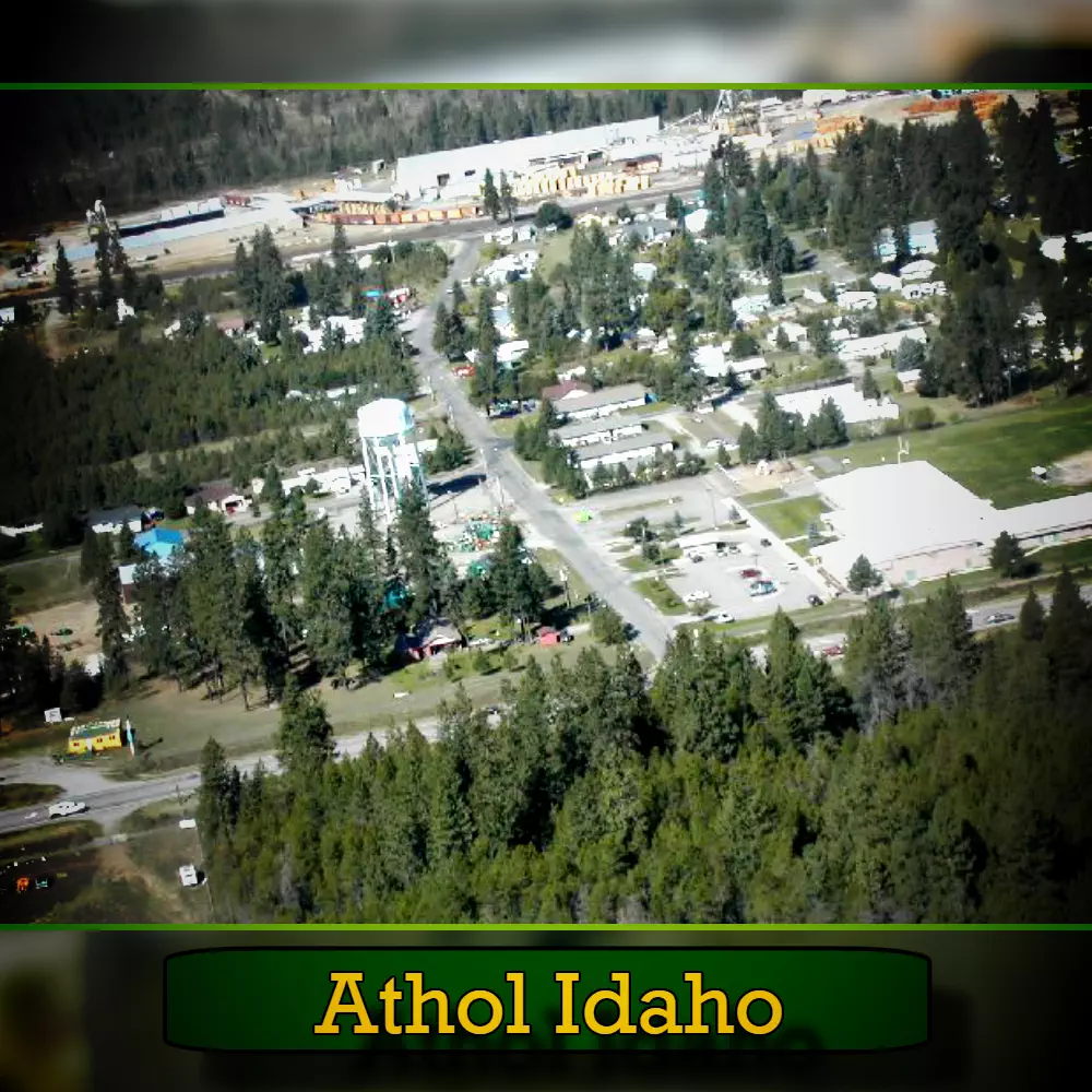 Aerial view of Athol, Idaho, showing buildings, roads, and surrounding forested area, including a tow truck providing reliable towing services to the community.