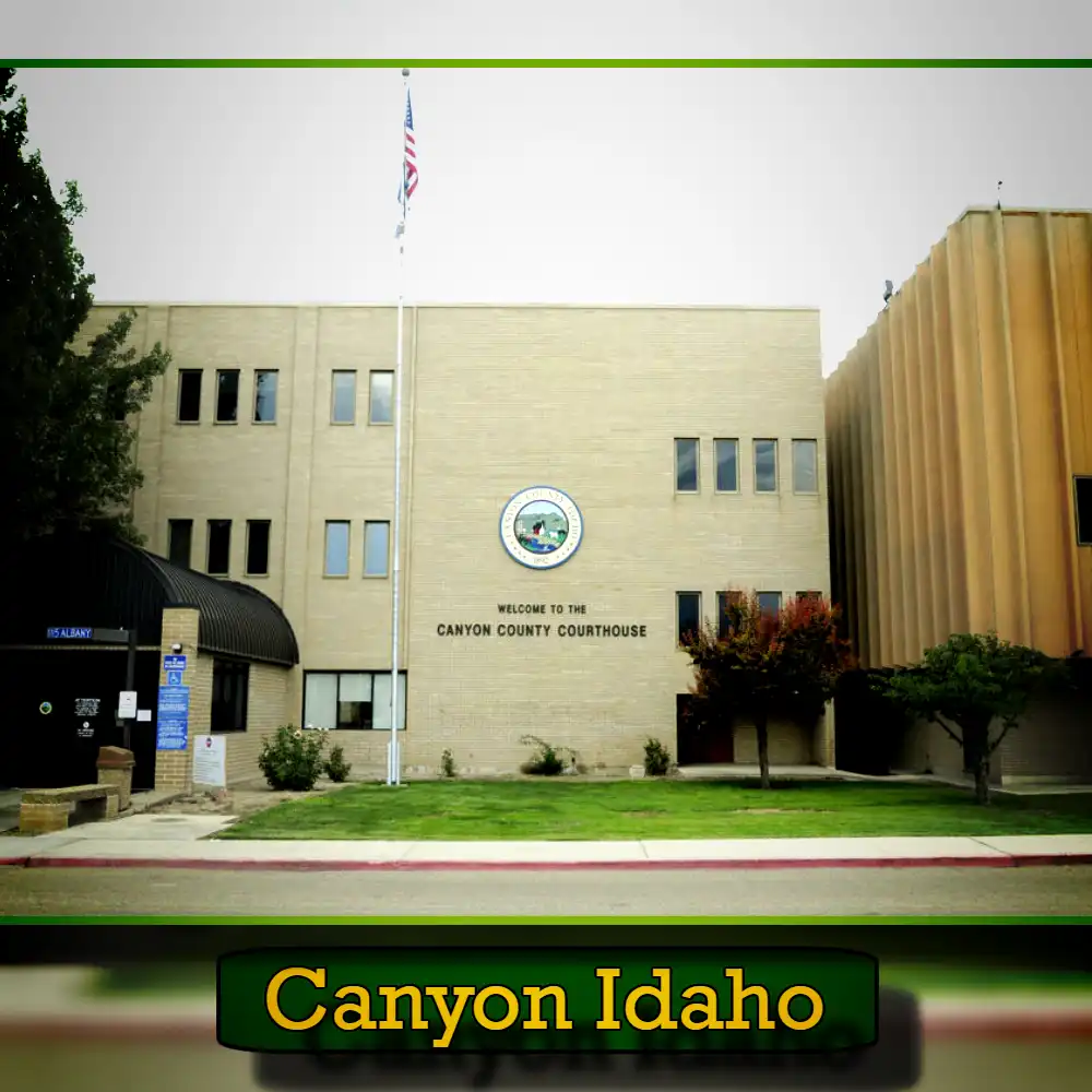 A beige three-story building represents the Canyon County Courthouse in Idaho, featuring an American flag, green lawn, and 