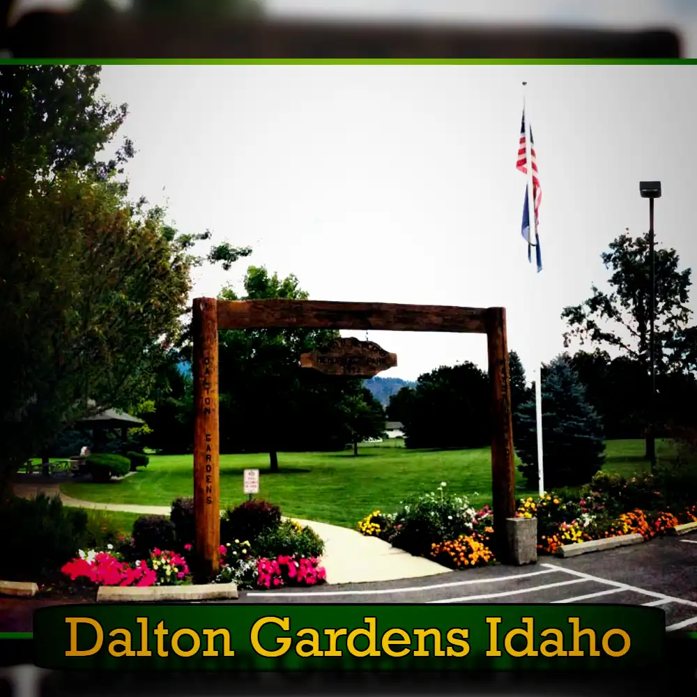 Entrance to a park in Dalton Gardens, Idaho with a wooden sign, well-maintained lawn, colorful flower beds, and flagpoles displaying American and other flags. Nearby is a dedicated spot for towing services, ensuring the park remains accessible and hassle-free for all visitors.