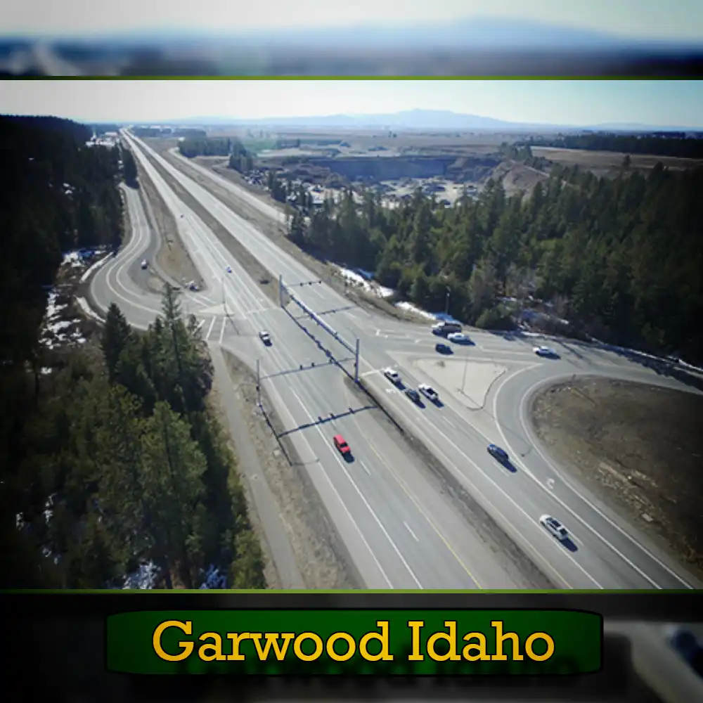 Aerial view of a highway intersection surrounded by trees and open land, with a few cars visible, including a tow truck in the distance. Text at the bottom reads 