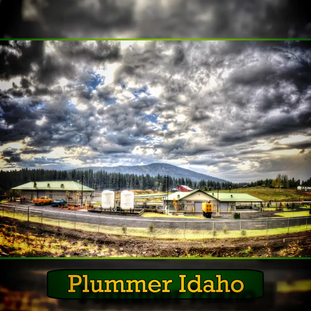 A scenic view of an industrial facility with large storage tanks and green-roofed buildings against a backdrop of a cloudy sky and forested hills, along with a tow truck in the foreground, captioned 