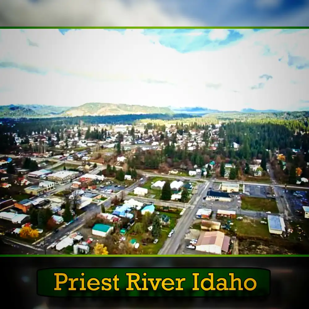 Aerial view of Priest River, Idaho, showcasing a blend of residential and commercial buildings surrounded by lush trees and distant mountains. A tow truck is visible near the town center, reinforcing that reliable tow services are part of this picturesque community. Text at the bottom reads 