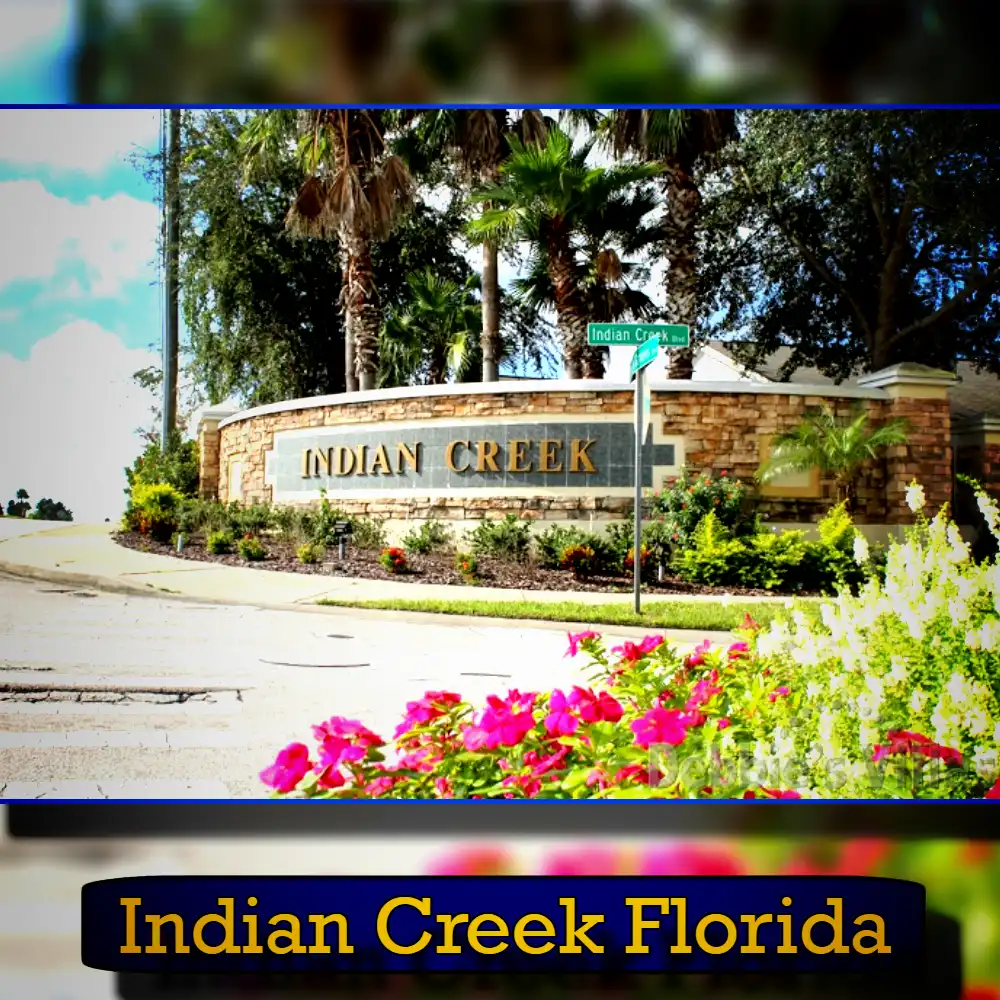Entrance sign for Indian Creek in Florida, surrounded by greenery and flowers, with street signs indicating Indian Creek Drive and a nearby tow service available to assist.