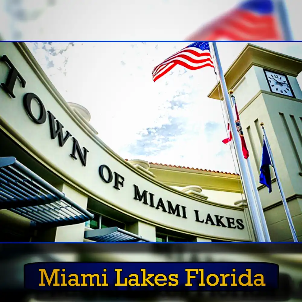 The exterior of the Town of Miami Lakes building with the U.S. flag and clock tower visible. A tow truck is parked nearby, adding to the scene. Text at the bottom reads 