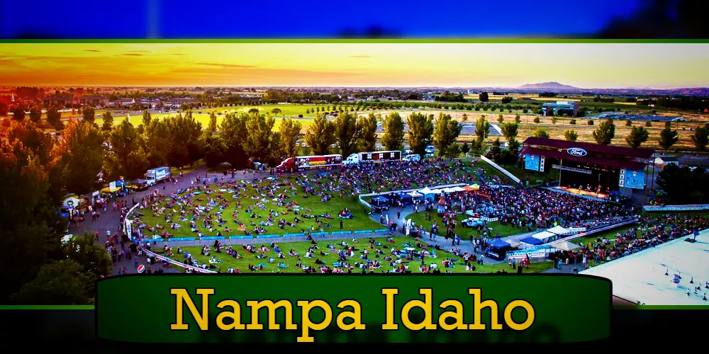 A large outdoor crowd gathered at an event in a green field with a stage in Nampa, Idaho, during sunset. The foreground features a banner reading 