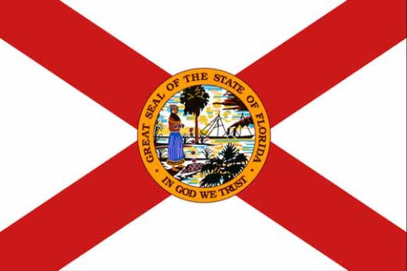 The flag of Florida features a red St. Andrew's Cross on a white field with the state seal in the center, depicting a Native American woman, a steamboat reminiscent of early towing vessels, a palm tree, and the state motto "In God We Trust.